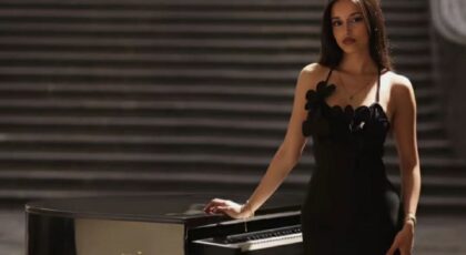 mladá slečna ve večerních šatech stojící u piána